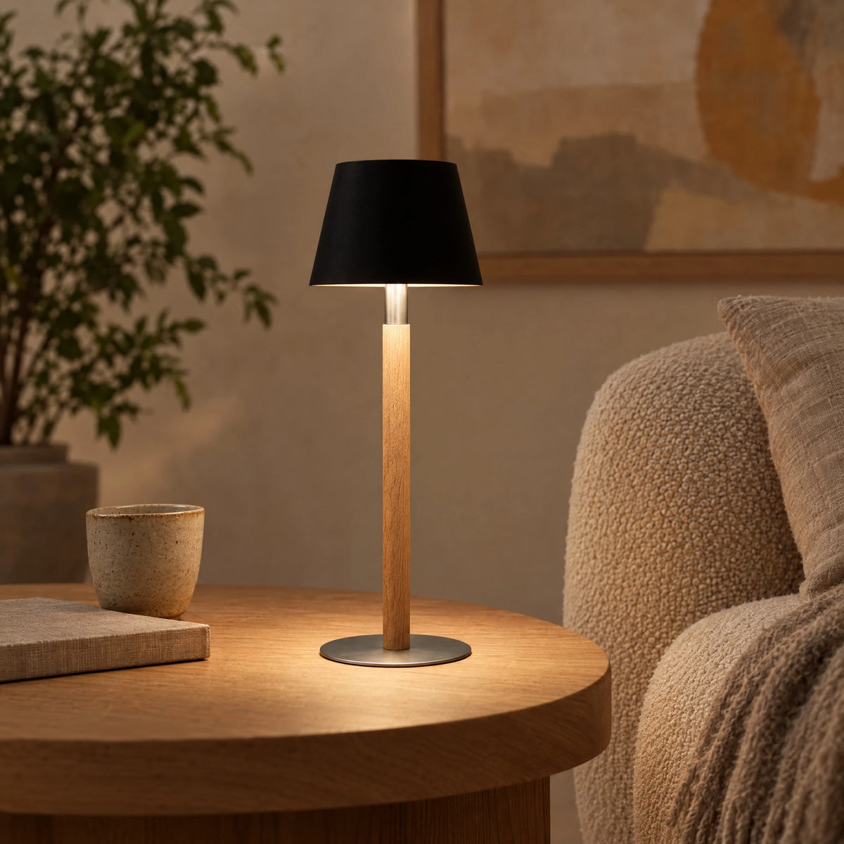 Nala rechargeable table lamp in solid oak with steel base and black shade, cordless on the dining table
