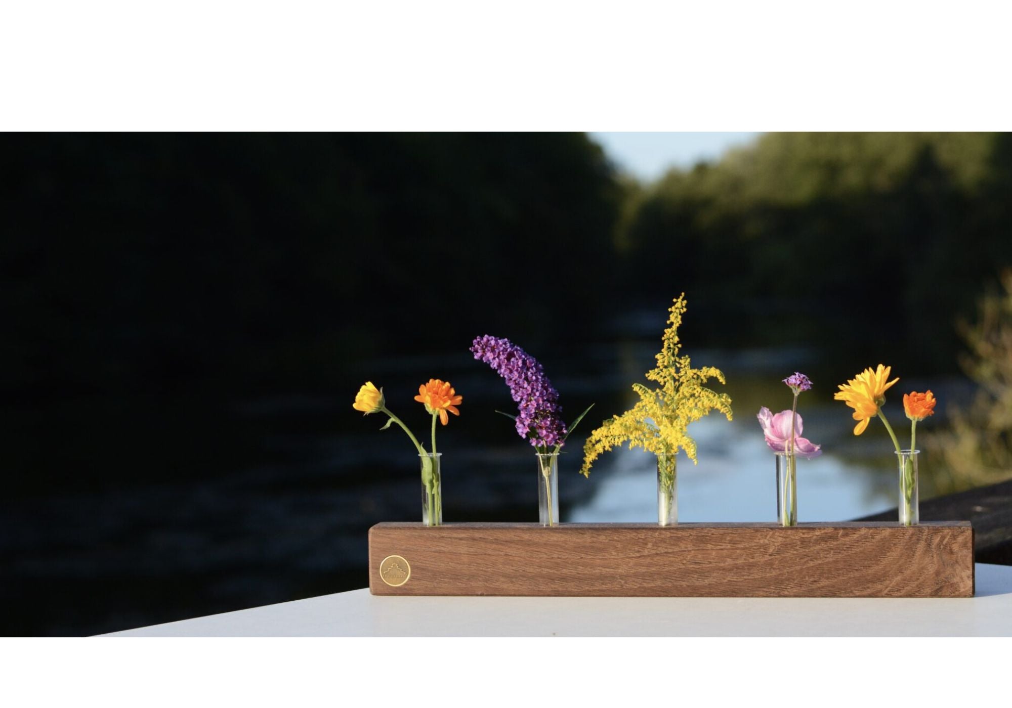 Nachhaltige Vasenleiste vor malerischem Flussufer, stilvolle Holzverarbeitung und umweltfreundliche Accessoires von SpeicherArt.