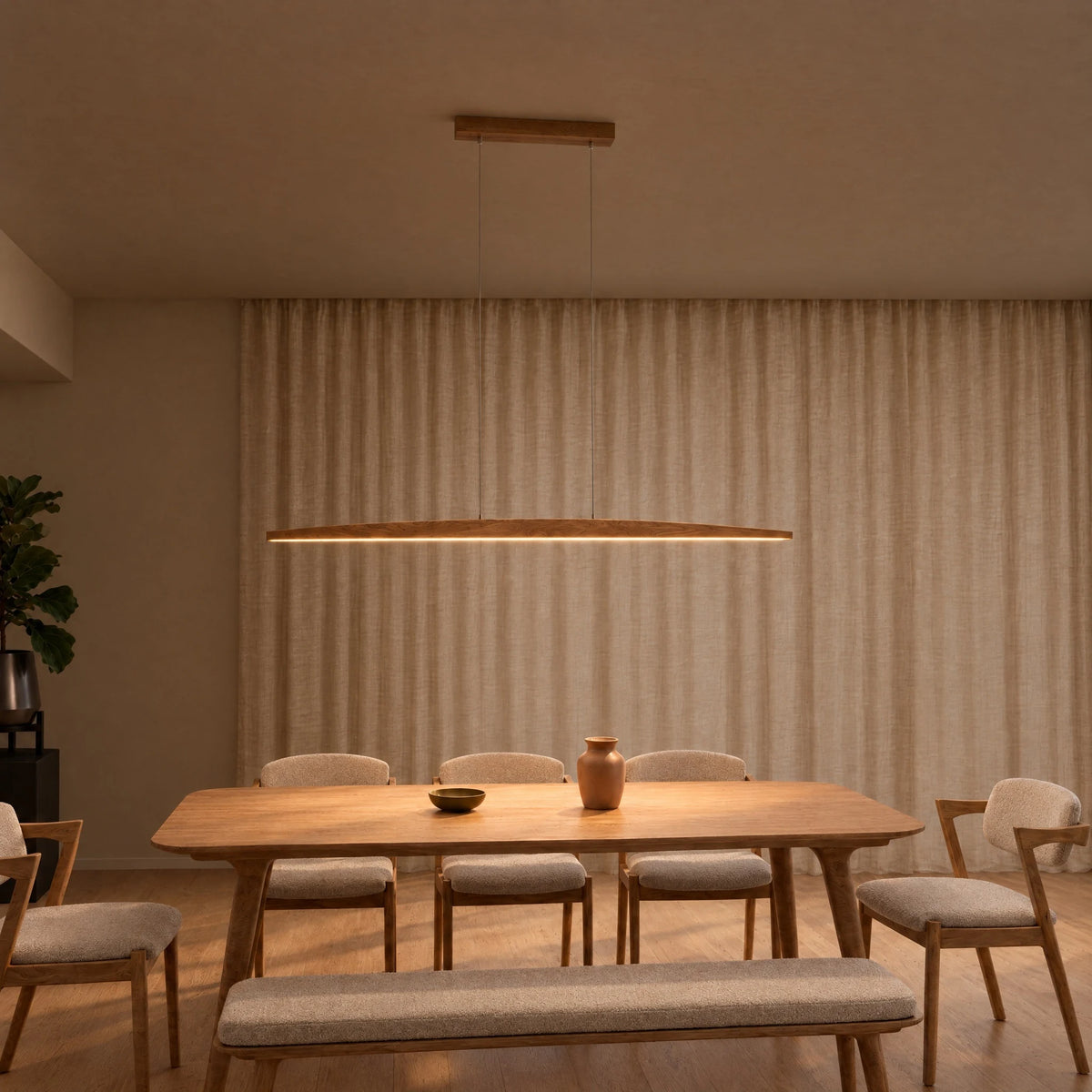 SpeicherArt Elia pendant light: slim, curved solid oak body, switched on above a wooden dining table in front of a light linen curtain