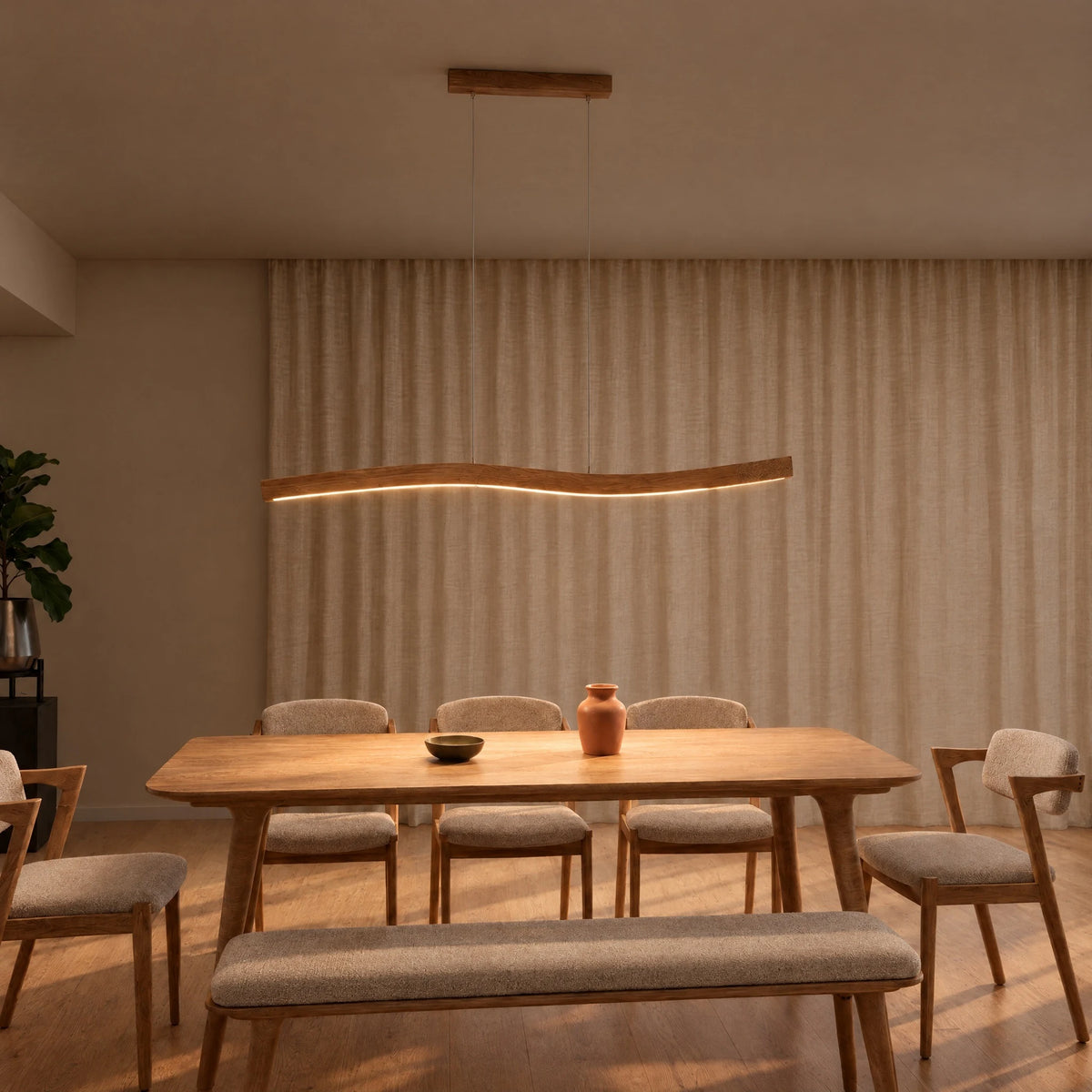 SpeicherArt Lyra pendant light: gently curved solid oak light, switched on above a wooden dining table in front of a light linen curtain