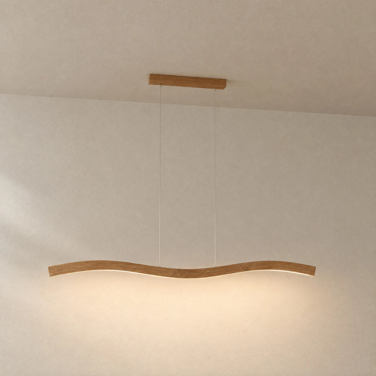 Mila oak pendant light hanging freely against a light plaster wall, double-curved form