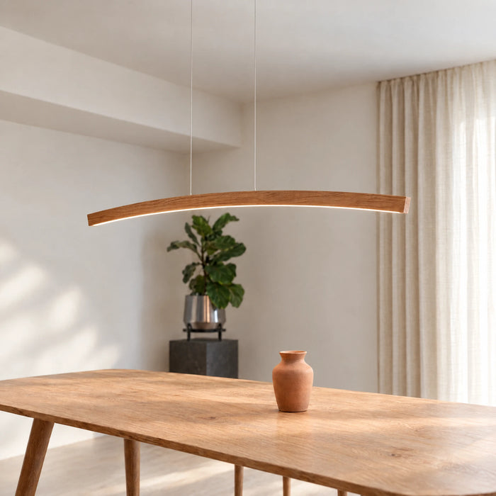 Novara pendant light by SpeicherArt: curved arc in solid oak with a light line on the underside, above a dining table