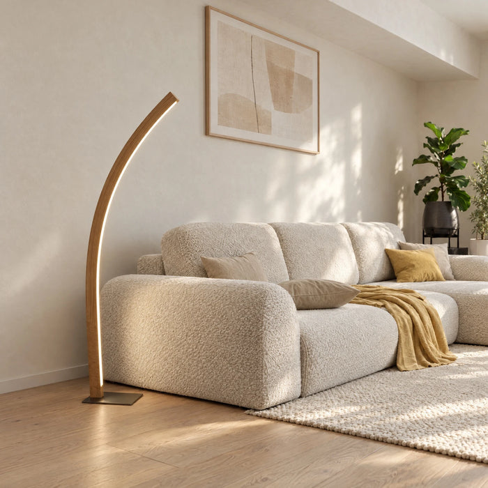 Solara floor lamp in solid oak: curved arc lamp with LED light line beside a sofa in the living room